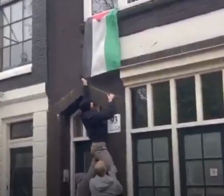 Un israelí sionista arranca una bandera de Palestina de una propiedad privada en Ámsterdam, horas antes de los incidentes